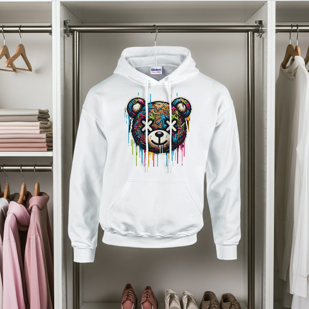White hoodie with a colorful bear design hanging in a wardrobe.