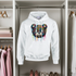White hoodie with a colorful bear design hanging in a wardrobe.