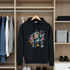 Black hoodie with colorful bear graphic hanging in a wardrobe.