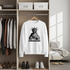 White sweatshirt with a graphic design of a statue of liberty on a hanger in a wardrobe.