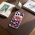 Phone case with colorful floral design on a wooden table with books and a vase.