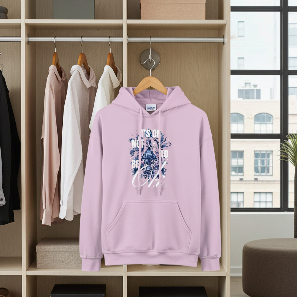 Pink hoodie with floral design and text on a wooden rack with other clothes.