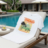 White t-shirt with tropical design on a lounge chair by a poolside.