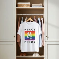 White t-shirt with rainbow design and 'Peace & Pride' text hanging in a closet.