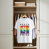 White t-shirt with rainbow design and 'Peace & Pride' text hanging in a closet.
