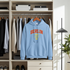 Light blue hoodie with 'BERLIN 1994' text hanging in a wardrobe.