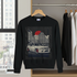 Black sweatshirt with car graphic on a hanger in a room with a cityscape view.